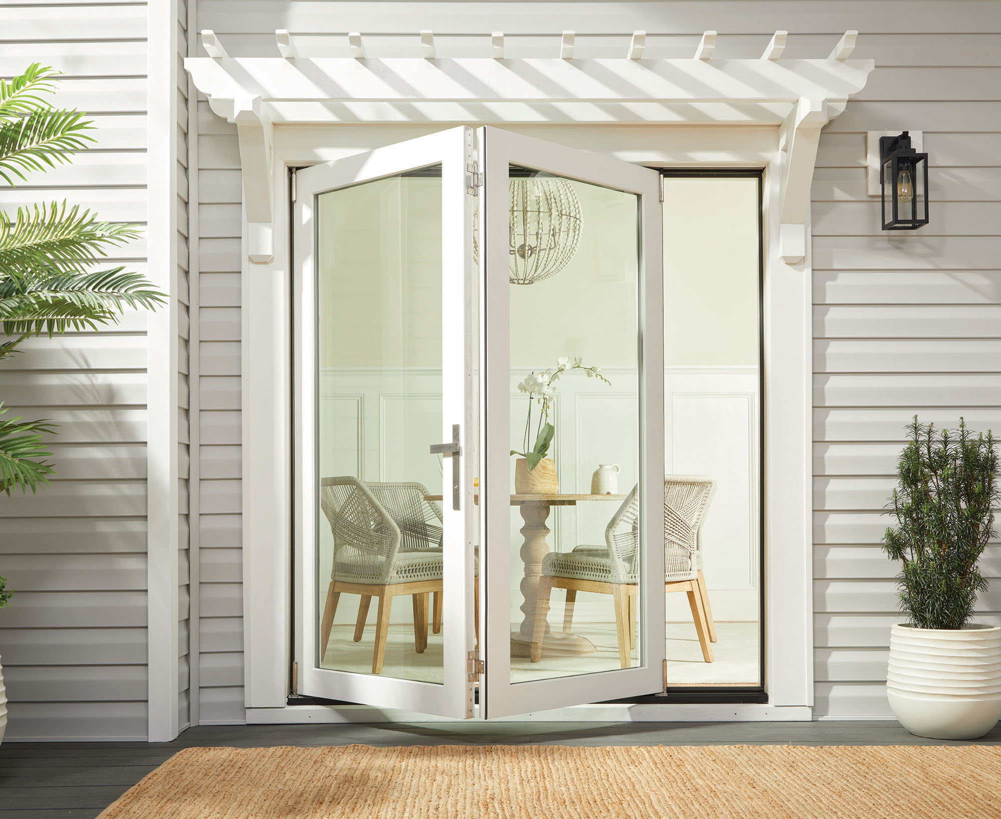 F-4500 folding patio door in white with a pergola and woven deck mat